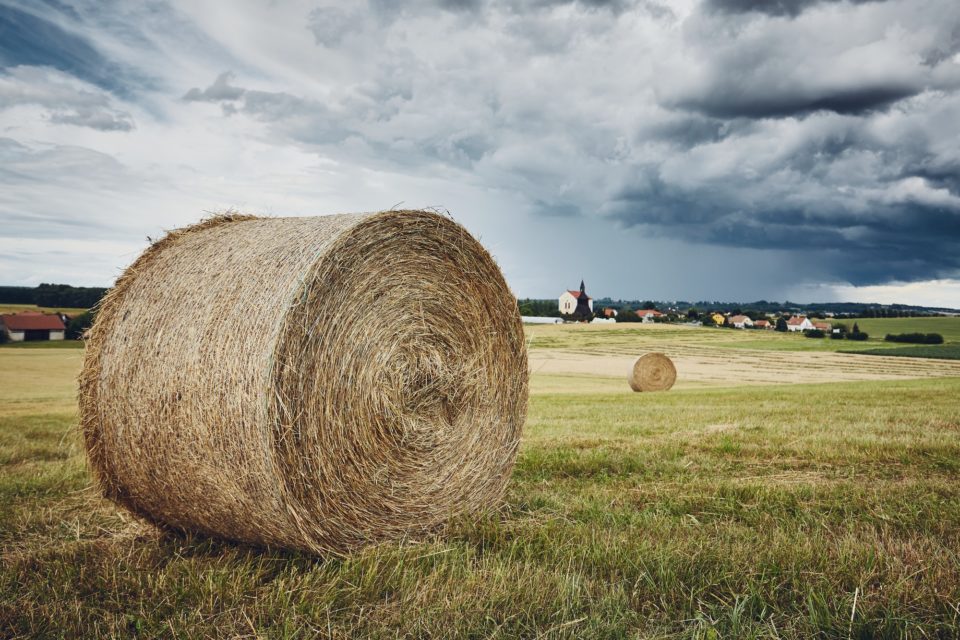 Straw bales stacked on field against storm