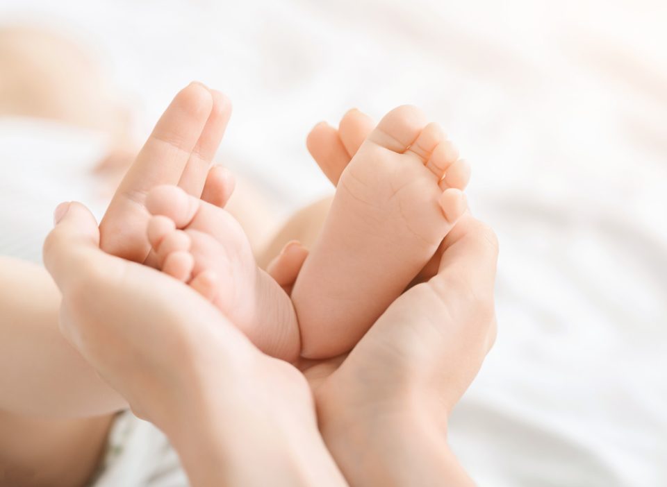 Newborn baby feet in mother hands closeup