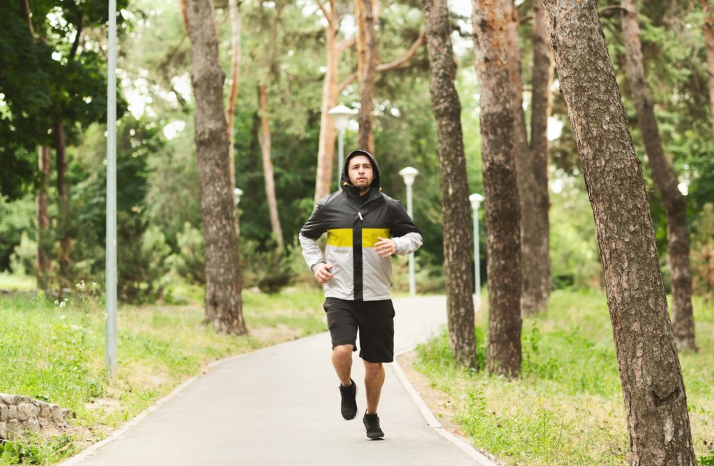 Young sporty man jogging in autumn park