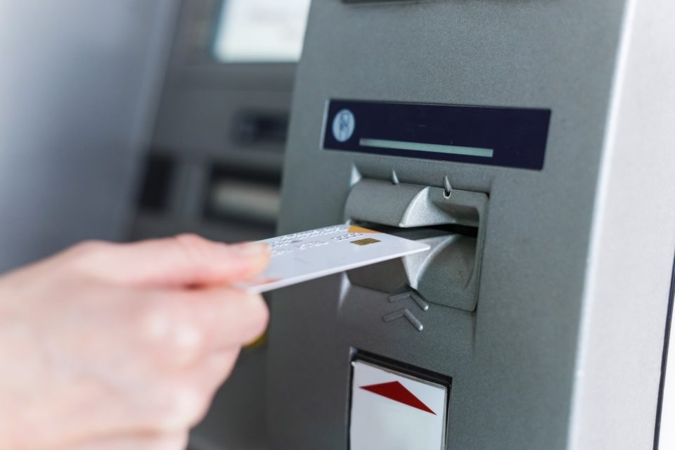 Person insert card to automated teller machine. Cashing non-cash money by individual.