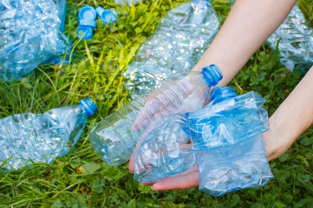Bottles of mineral water in hand of woman, littering of environment