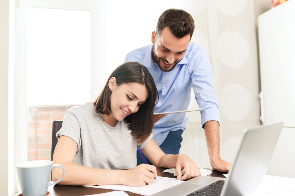 Content confident young man using tablet app while assisting girlfriend