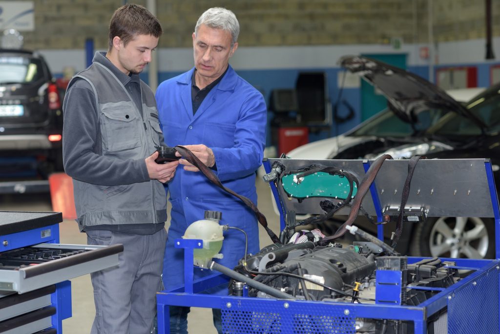 teacher and student in auto mechanics training class