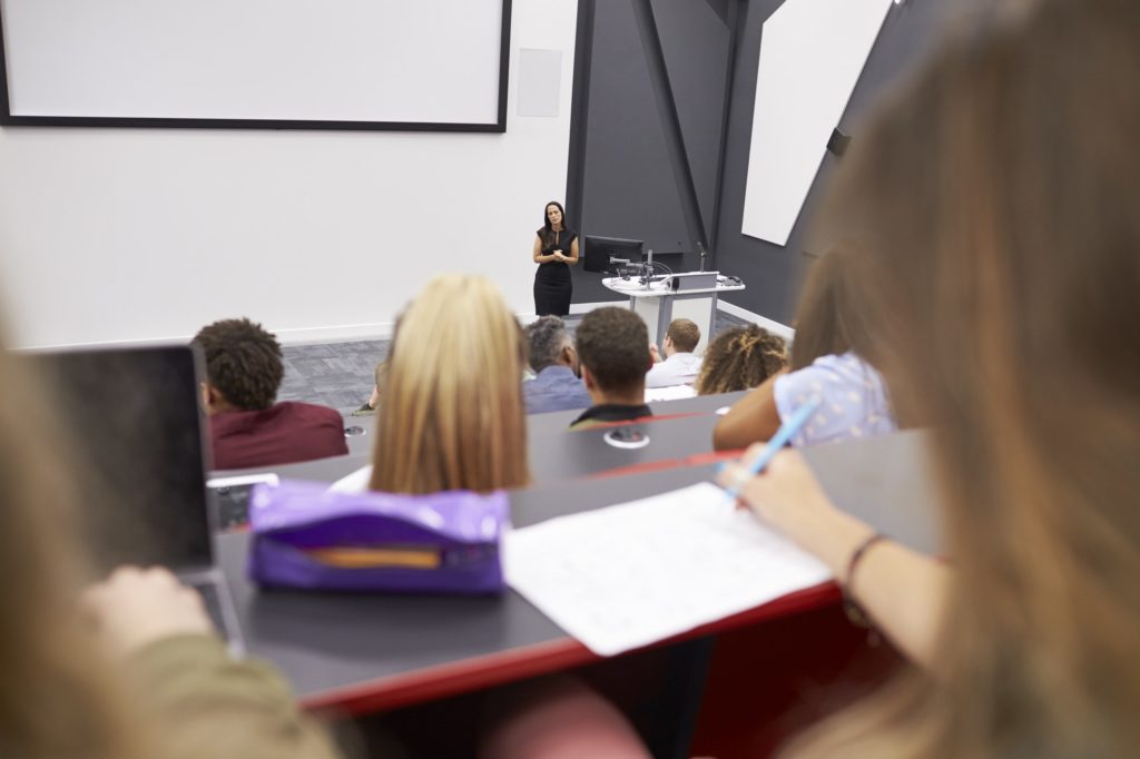 Woman lecturing students in a lecture theatre, student POV