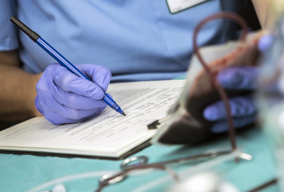 Nurse writes down blood transfusion data in a hospital, concept picture