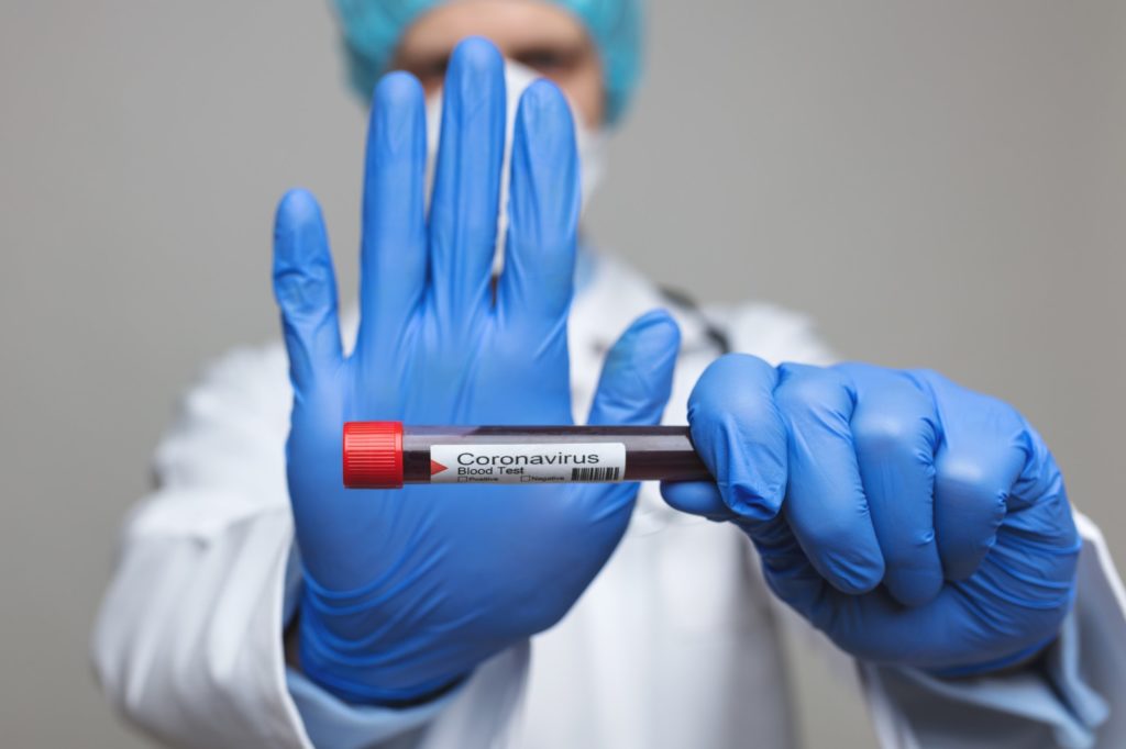 Doctor wearing respiratory mask and holding the Coronavirus blood sample