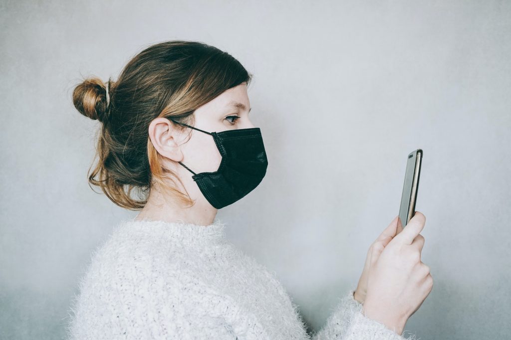 Young woman wearing a mask while use her smartphone