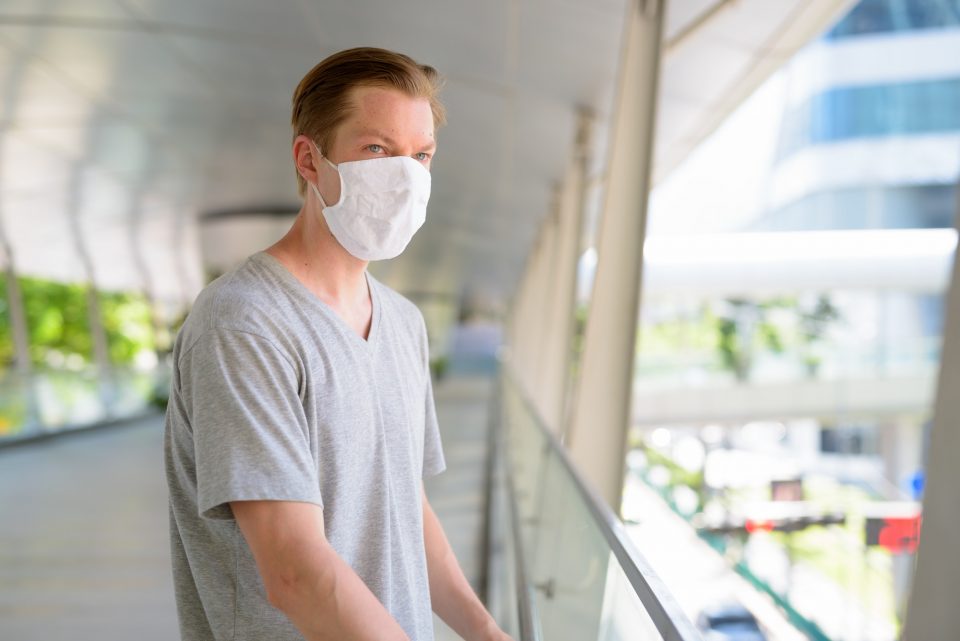 Young man looking at view of the city with mask for protection from corona virus outbreak