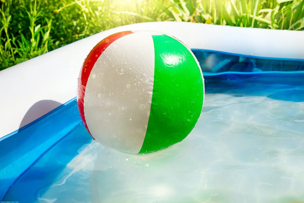 Beach ball floating in swimming pool in the yard.