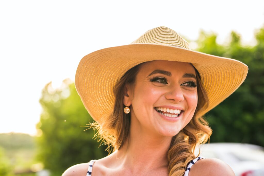Portrait of pretty cheerful woman wearing straw hat in sunny warm weather day.