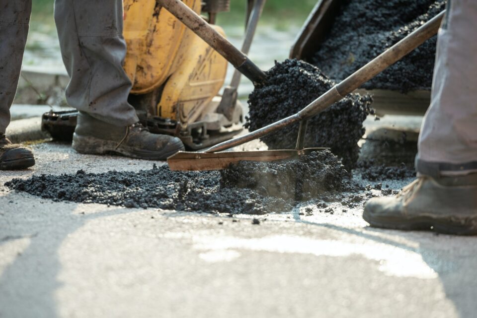Two construction workers patching bump in the road