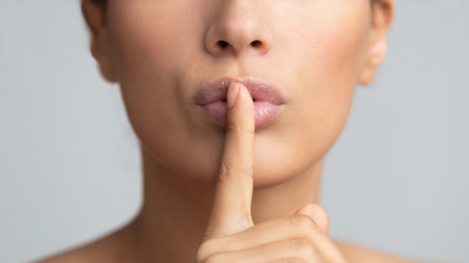 Women's secret. Woman holding finger on lips