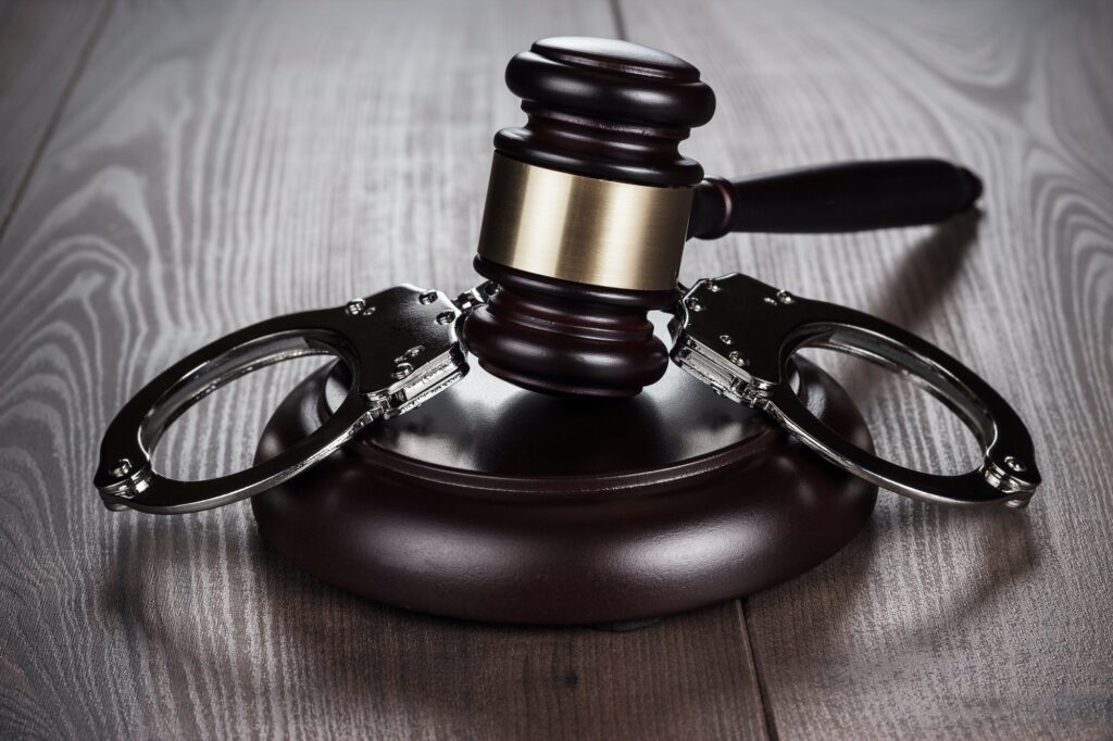 Handcuffs And Judge Gavel On Brown Table