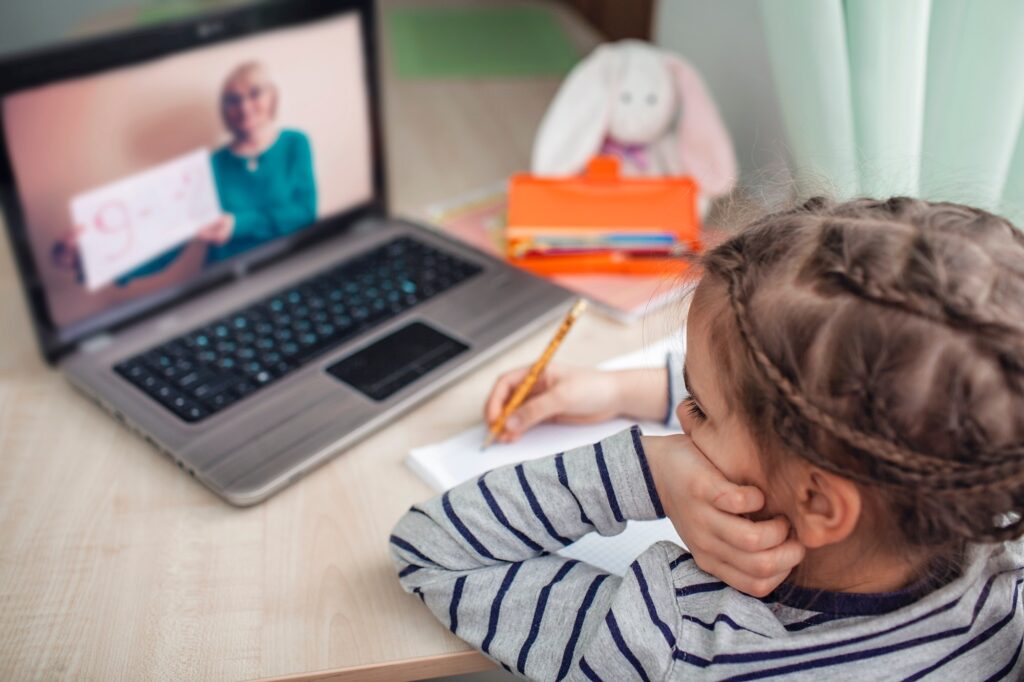 Pretty stylish schoolgirl studying math during her online lesson at home