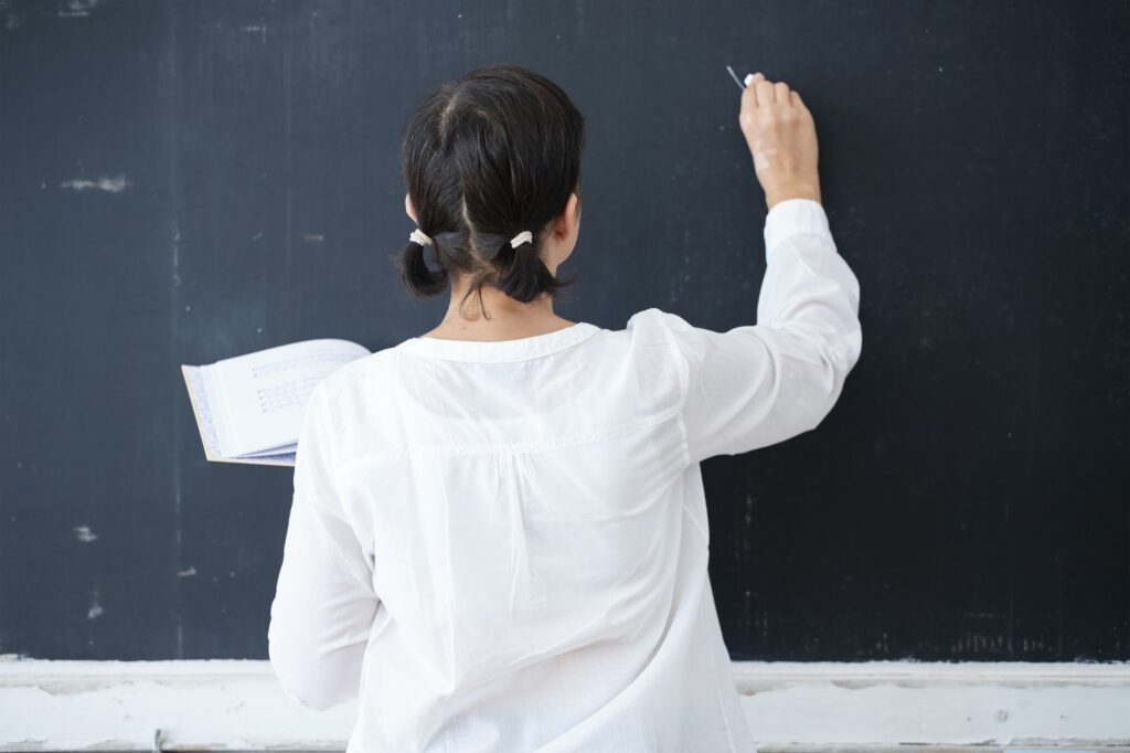 Teacher writing on blackboard in the classroom