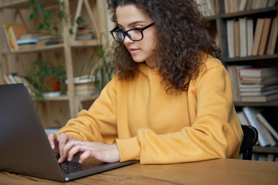 Hispanic teen girl school student using laptop elearning online.