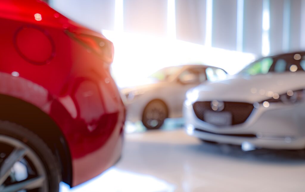 Blurred of white and red luxury car parked in modern showroom. Car dealership office. Electric car.