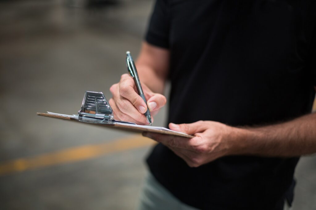 Factory staff writing on clipboard in factory