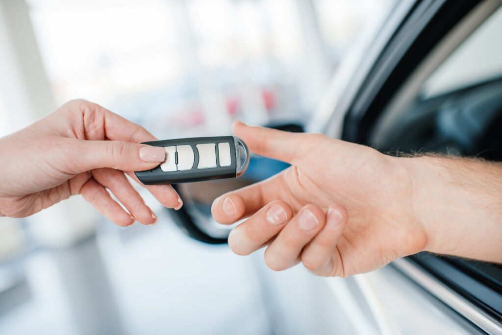 Close-up partial view of dealer giving car key to new owner