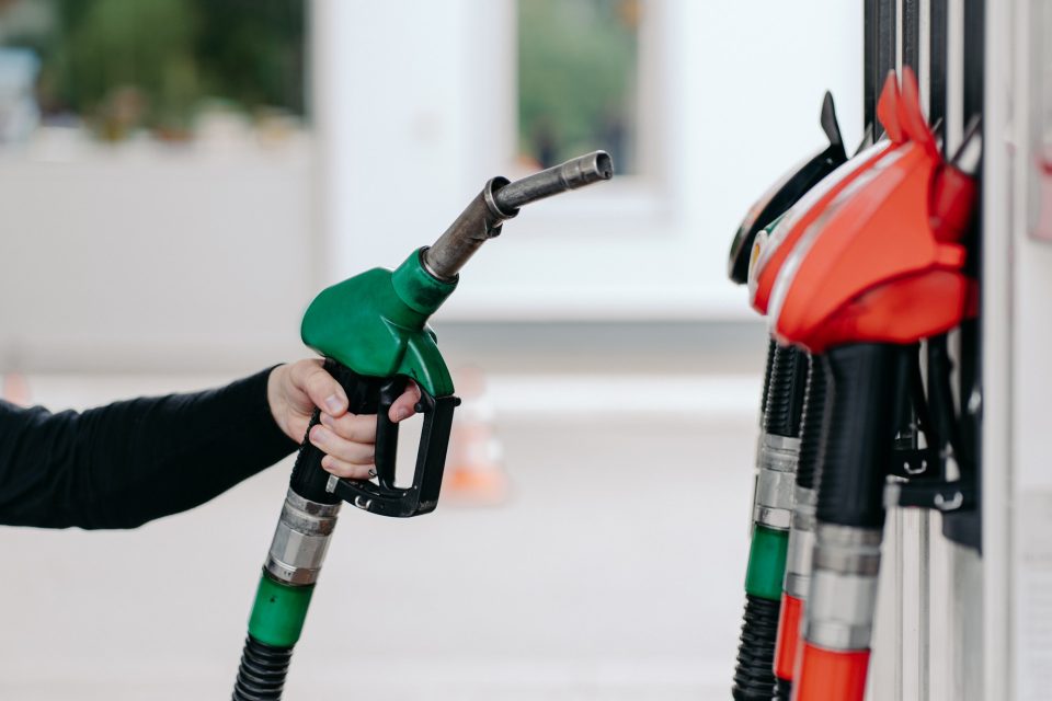 Mans hand using fuel nozzle at petrol station