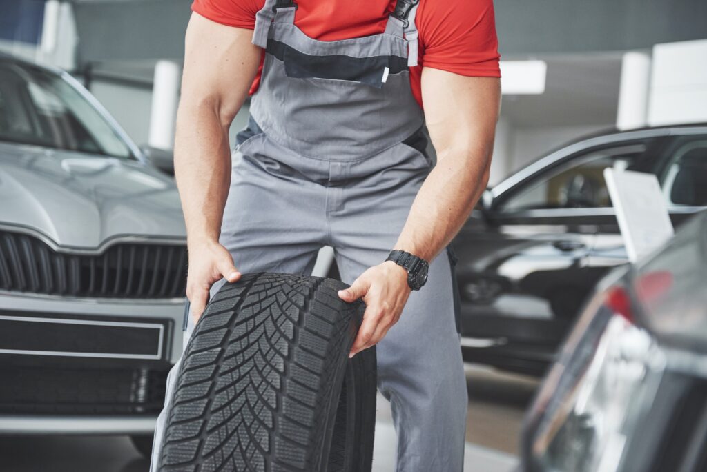 Mechanic holding a tire tire at the repair garage. replacement of winter and summer tires