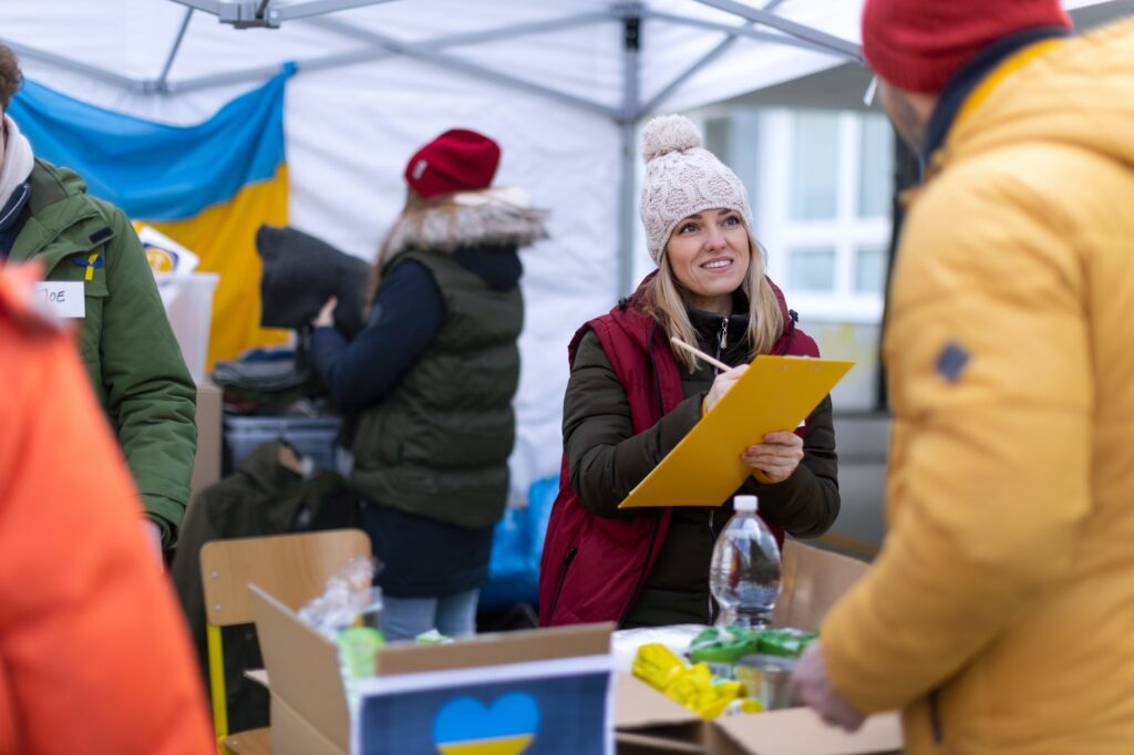 Volunteers distributing food and drink to refugees on the Ukrainian border, humanitarian aid concept