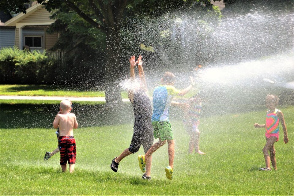 Kids having fun running through the sprinklers on a hot summer day