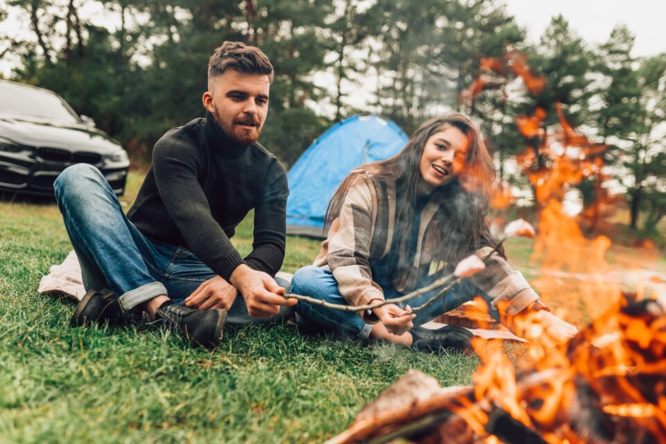 Pretty couple near the campfire makes roasted marshmallows