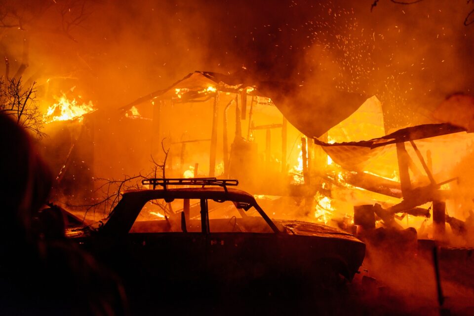 House fire at night with burnt car in smoke