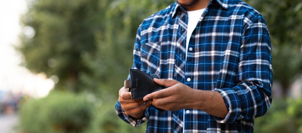 Cropped image of black guy looking at his empty purse