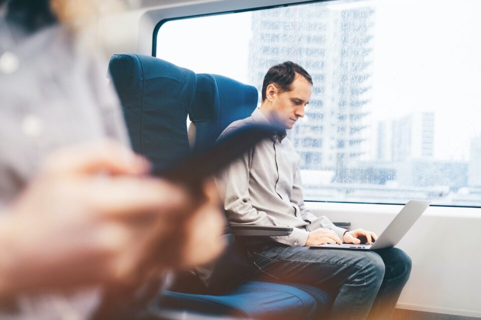 Man working on laptop at the train. Businessman traveling on train.