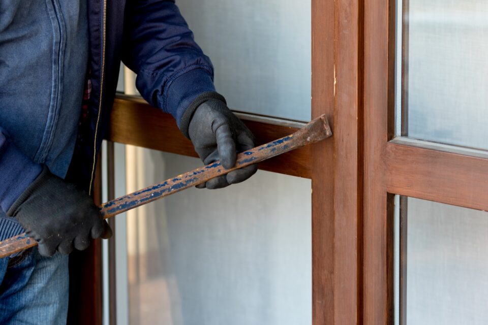 A thief trying to burden a window door with the crowbar