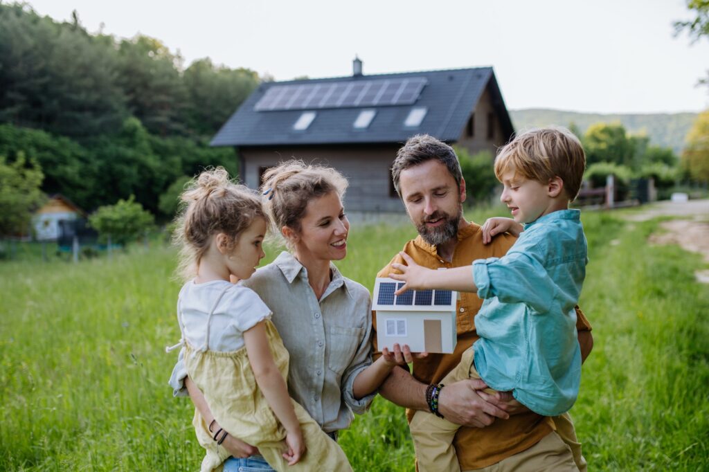 Happy family in front of their house with solar panels on the roof.